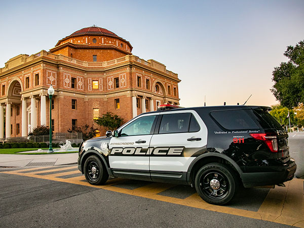 Image of police department vehicle with the Historic City Hall building in the background.