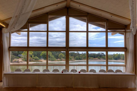 Image looking out a large window at the Pavilion on the Lake with table setting in the foreground.