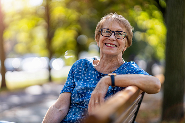 A smiling older woman on a bench