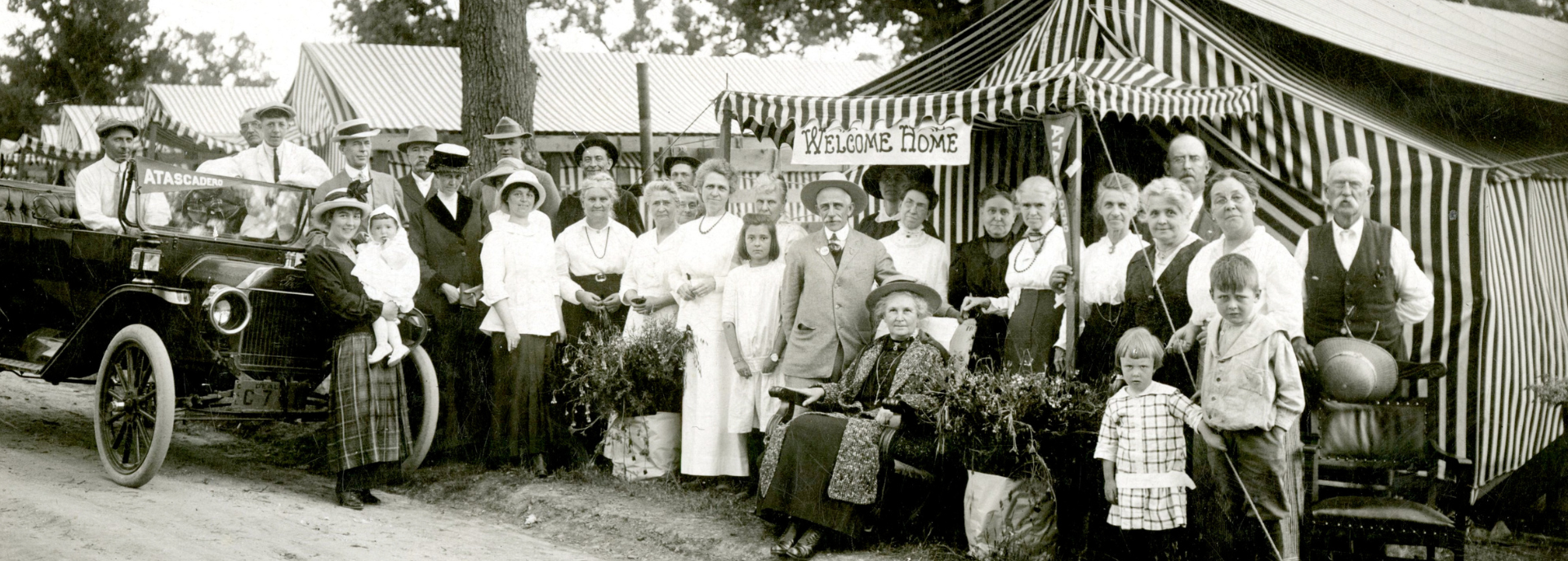 Historic photo of people at Tent City with a "Welcome Home" sign.