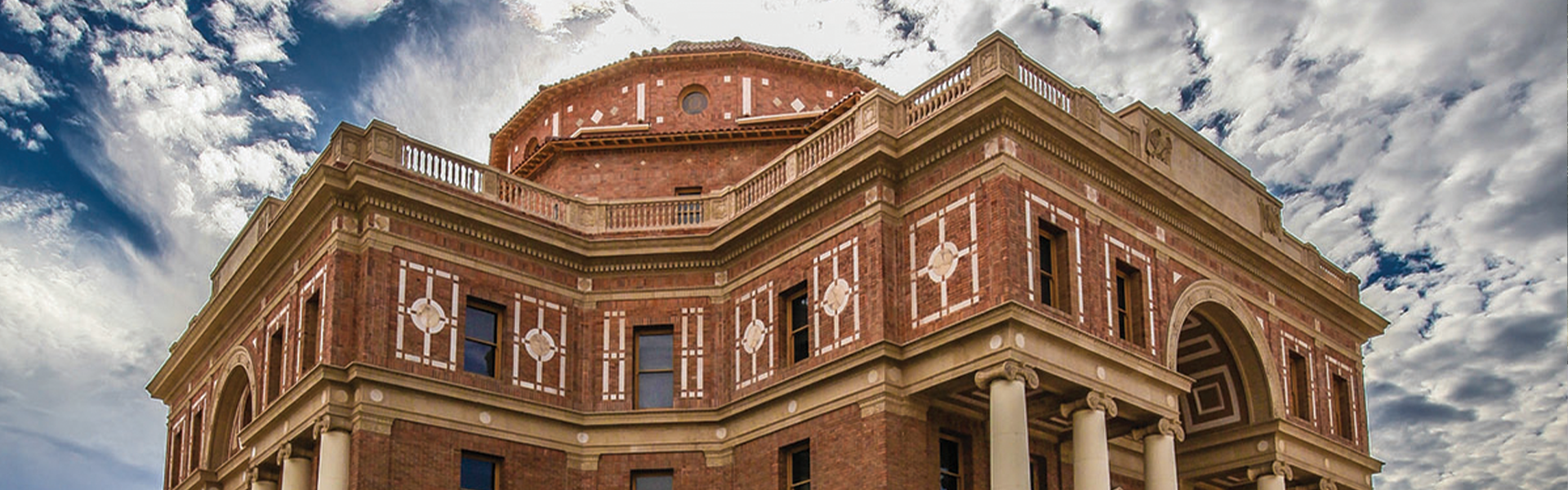 Up angle view of the Atascadero Historic City Hall building against blue sky with scattered clouds.