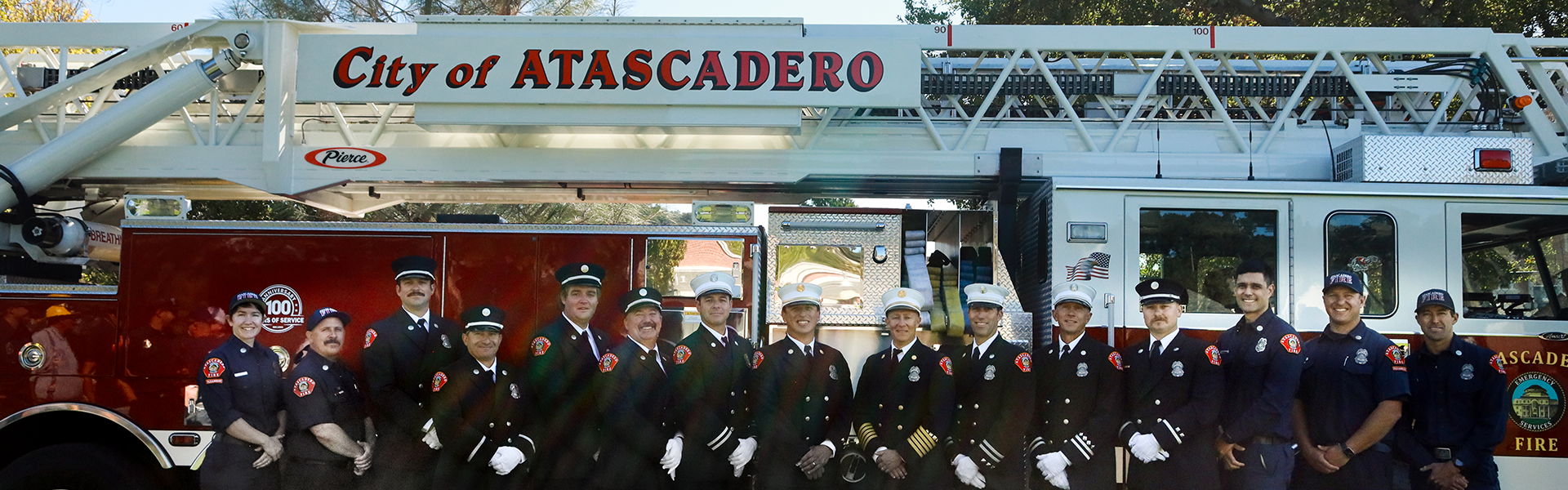 Image of Fire & Emergency Services staff in formal dress with a fire engine.