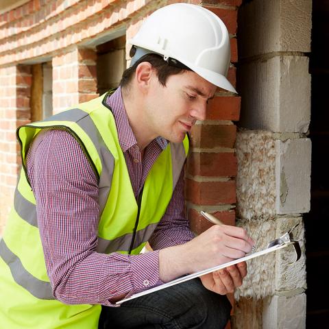 Man inspecting a crawl space of a house