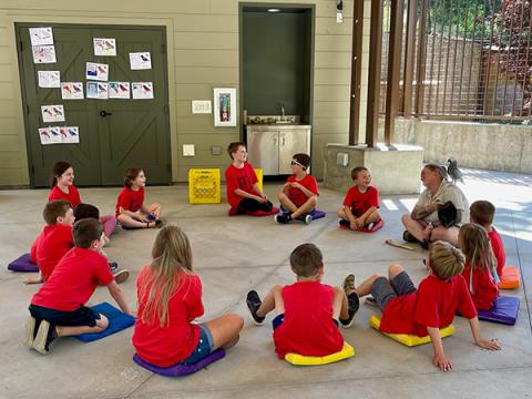 Children at Zoo Camp sitting in a circle with the camp instructor.