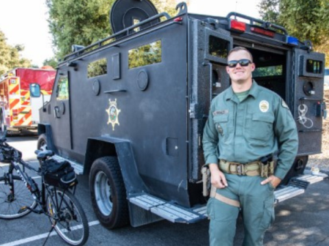 Officer standing in front of a special response vehicle at an event.