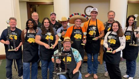 Group photo of the 2026 Best Overall Tamale judges at the Atascadero Tamale Festival, standing together holding trophies and wearing aprons decorated with tamales and the words “Masa Madness.”