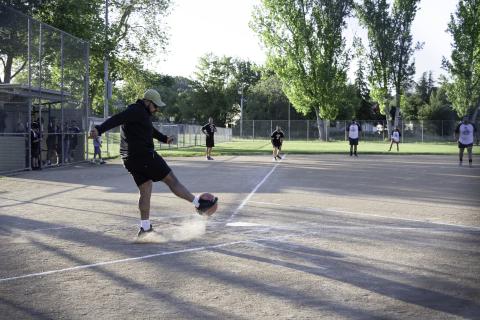 A man kicking the kickball during an adult kickball game!