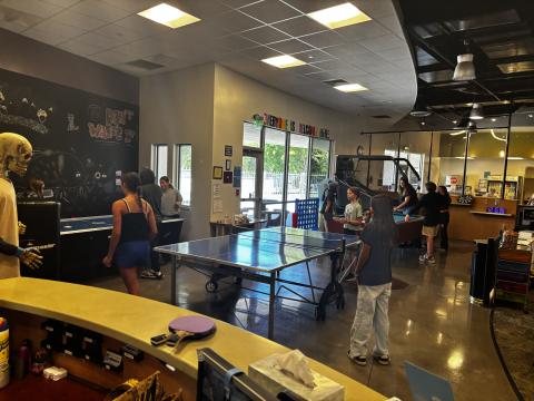 A wide shot of the Teen Center full of teens playing games such as air hockey, ping pong, pool, and mini basketball.