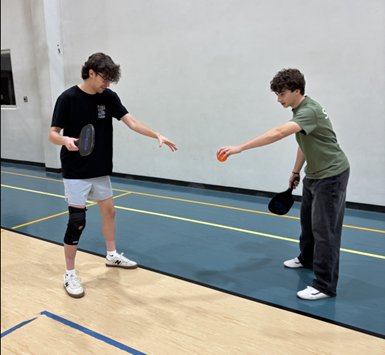 Coach Trey instructs a youth pickleball class participant