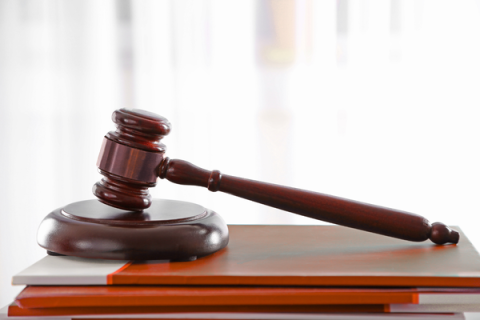 Wooden gavel resting on a stack of leather-covered document holders.