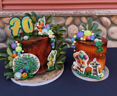 Close up image of 70th year birthday celebration cakes for the Charles Paddock Zoo, newly renamed, The Central Coast Zoo. The cakes featured celebratory decorations, with small disco balls, greenery and cute animal cutouts.