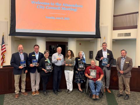 Members of the Atascadero City Council, the City Manager, Public Works Director, Community Development Director, and an American Planning Association representative stand smiling in front of the Council Chambers dais during the June 9, 2026, City Council meeting, in recognition of the El Camino Real Downtown Safety and Parking Enhancement Project receiving multiple awards.