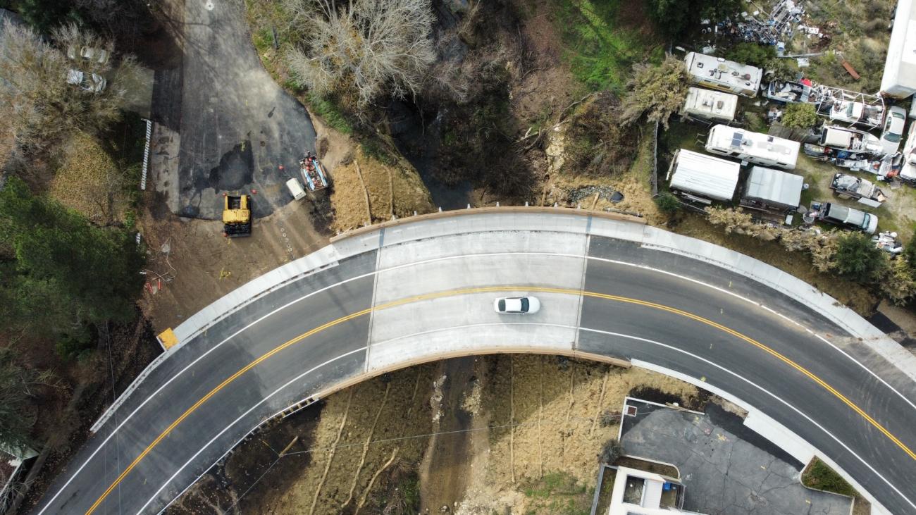Drone view from above of a car driving over the recently completed Via Avenue Bridge
